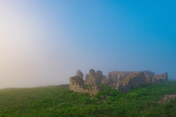 the ruins of the house in the mountains in the early foggy morning