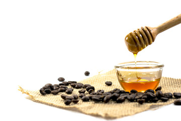 the Honey dipper and fragrant honey into a transparent bowl isolated white background. with coffee bean