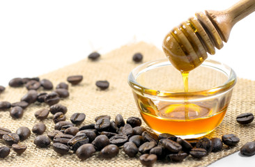 the Honey dipper and fragrant honey into a transparent bowl isolated white background. with coffee bean