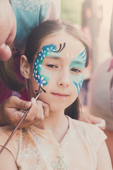 Female child face painting, making butterfly process