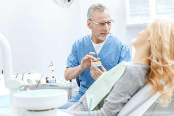 dentist showing jaws model to patient in dental clinic
