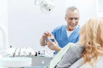 dentist showing jaws model to patient in dental clinic