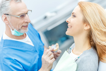 dentist showing jaws model to patient in dental clinic