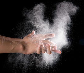 Obraz na płótnie Canvas Chef hand clap with splash of white flour and black background