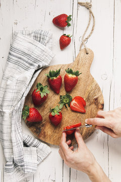 Woman hands cutting strawberries on tabletop