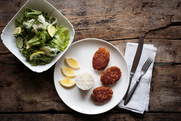 Overhead view of fish crocuettes with fresh green salad.