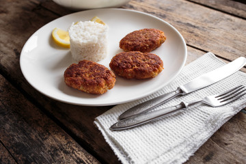 Three fish breadcrumbed cutlet on white plate with rice. Restaurant menu background