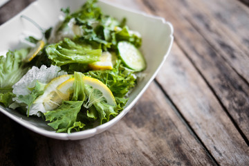 Fresh salad in white bowl on wooden background. Close up image of healthy food