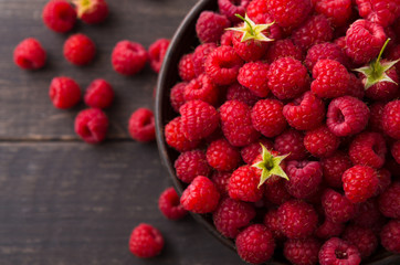 Red fresh raspberries on brown rustic wood background