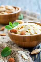 Almond flakes and whole almonds in wooden bowls.