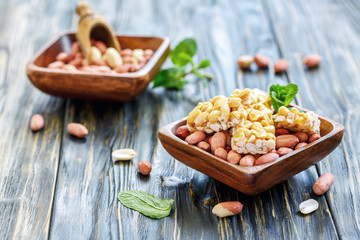 Honey bars with peanuts and whole peanuts in bowls.