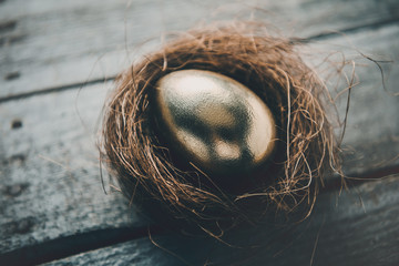Close-up view of golden Easter egg in nest on wooden table, Happy Easter concept