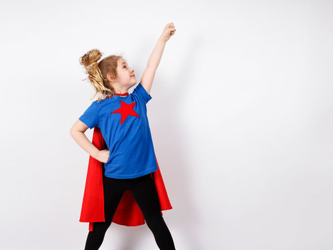 Six year blonde girl dressed like superhero having fun at home. White wall on background