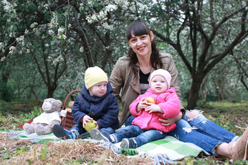 mother with twins in a spring apple flower garden 