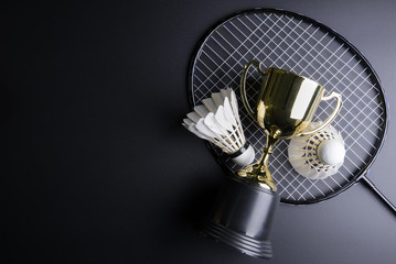 Golden trophy, Shuttlecocks and badminton racket on black background.Sport concept, Concept winner, Copy space image for your text.