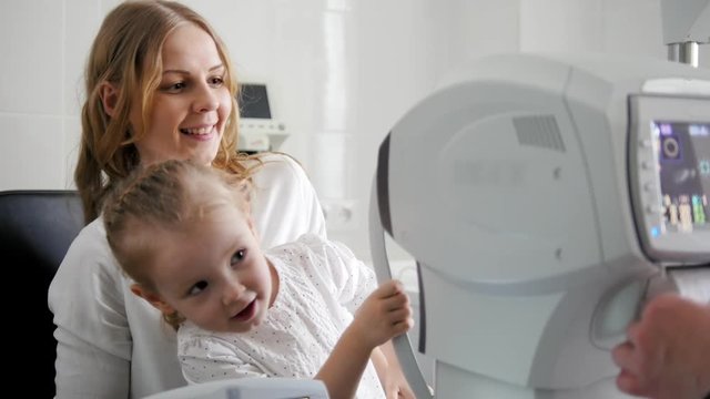 Optometrist in clinic checking little child's vision - pretty girl and doctor