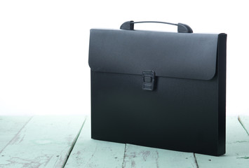 Black plastic folder for documents on wood, isolated over white