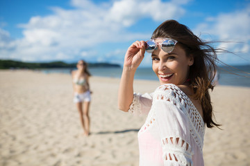 Happy beautiful woman standing on beach with friend laughing