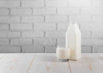 Fresh milk on wooden table against white brick wall