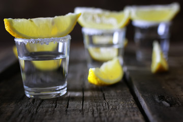 stack of tequila with salt and lemon on a wooden background
