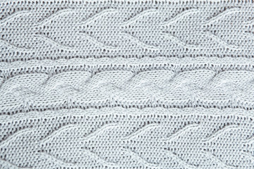 Beautiful light gray knitted pattern, knitted scarf close up. Knitted background