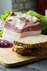 Salt pork lard with bread and herbs on a wooden board. Selective focus.