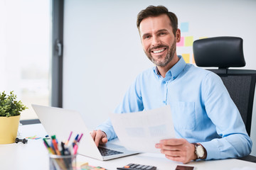 Happy businessman working with laptop at office