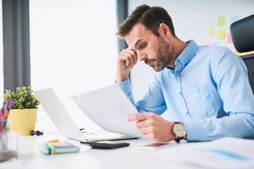 Naklejka premium Unhappy businessman doing paperwork at office