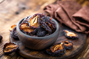 Prune, dried plums fruits on dark rustic wooden background