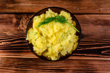 Mashed potatoes in glass bowl on wooden table. Top view