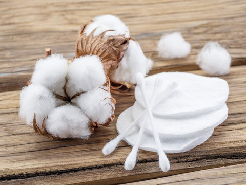 Fluffy cotton ball and cotton swabs and pads on wooden table.