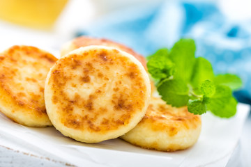 Cottage cheese fritters on white wooden background closeup