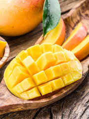 Mango fruit and mango cubes on the wooden table. © volff