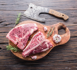 Steak T-bone with spices on the wooden cutting board.