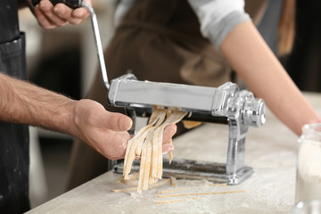 Young couple preparing pasta on kitchen table, closeup