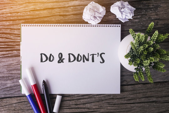 Do And Dont's word with Notepad and green plant on wooden background.