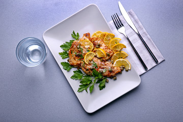Plate with tasty Italian chicken piccata on table