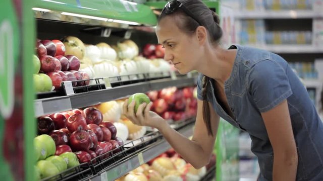 Woman selecting fresh apples in grocery store