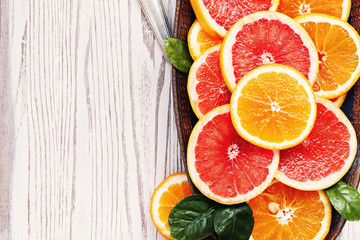 Variety  sliced citrus fruit orange, grapefruit, lemon on  wooden board. Top view.