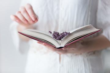 photo of young woman holding opened book with branch of lavender on the wonderful white background