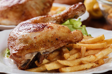 Roasted chicken legs with french fries and lettuce