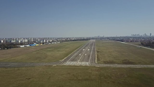 Aerial shot of a city airport plated runway on a sunny day. 4K video