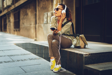 Young woman listening to music via headphones on the street