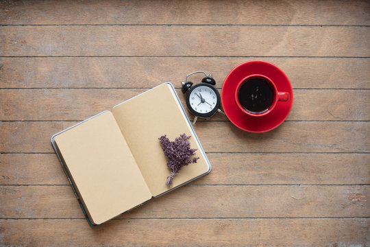photo of opened notebook, bunch of lavender, alarm clock and cup of coffee on the wonderful wooden brown background