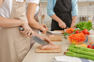 Woman cutting chicken fillet at cooking classes