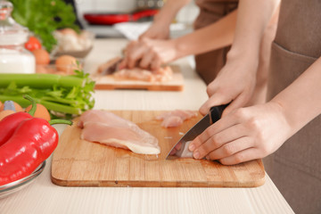 Woman cutting chicken fillet at cooking classes
