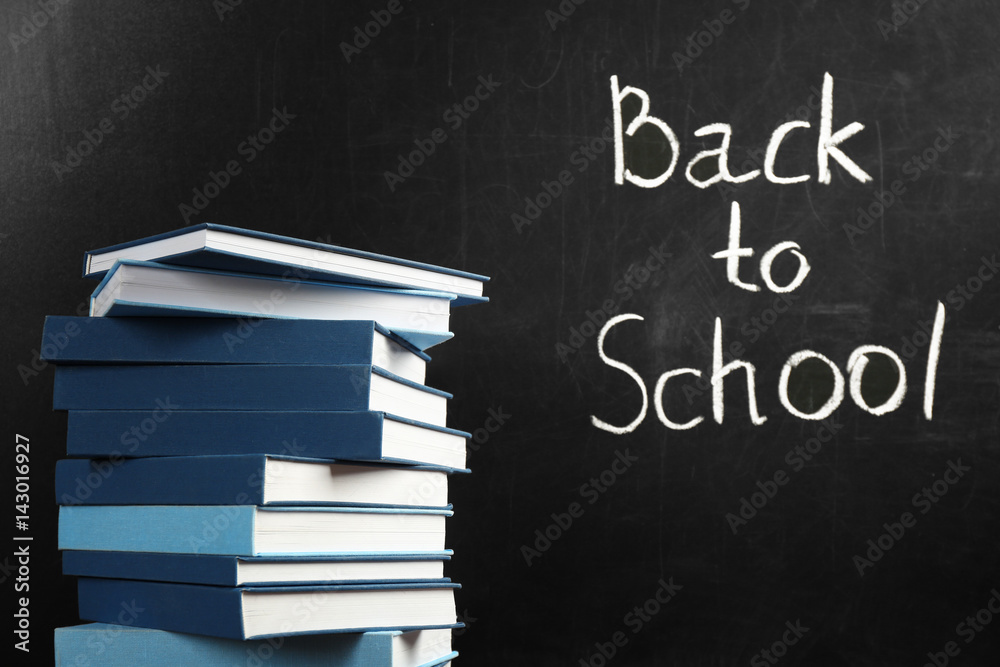 Wall mural Books on blackboard background. Back to school concept