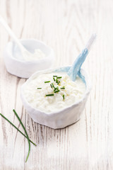 Rustic white bowl of homemade cottage cheese on a wooden marble table with copy space. Selective focus.