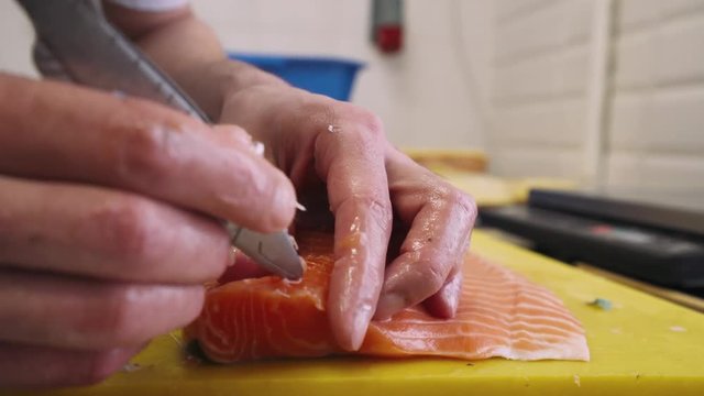 Сooking, the cook takes out bones from red fish, salmon.
