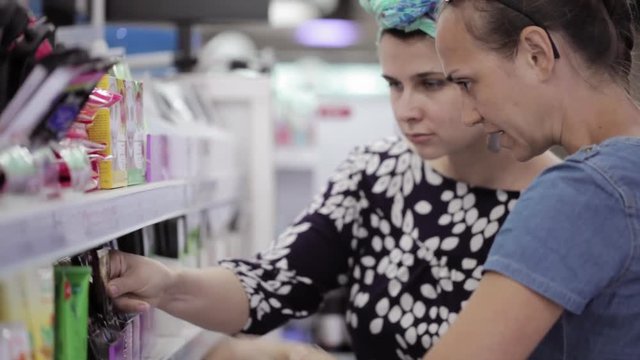 Two attractive womans choosing body care products In supermarket.